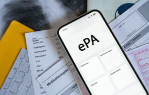 verschiedene medizinische Dokumente liegen übereinander, oben auf ein Smartphone auf dem 